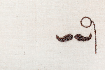 A monocle and a mustache made with coffee beans shot from above, aligned to the right.