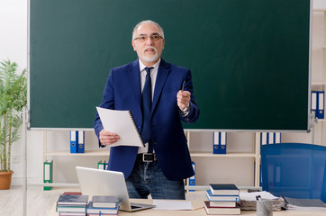 Aged male teacher in front of chalkboard 