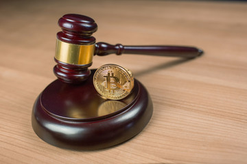 Bitcoin regulation. BTC cryptocurrency coin and judge gavel on a desk. Banned currency or law enforcement concept.