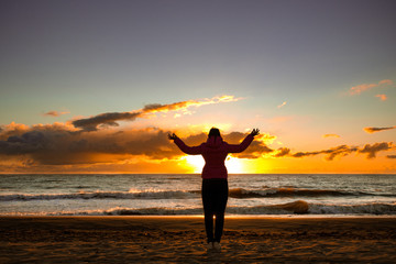 Fototapeta premium girl standing in a yoga pose at sunset by the sea