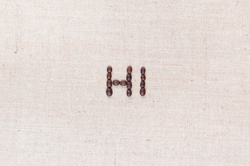 The word Hi written with coffee beans shot from above, aligned in the center, closeup.