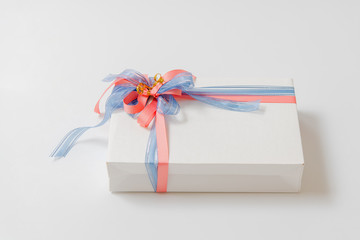 Luxury box tied with blue and pink ribbons on white background