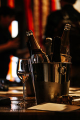 Fototapeta na wymiar wine tasting: on a wooden table there is a silver bucket for cooling wines with open bottles of champagne and a glass of wine.