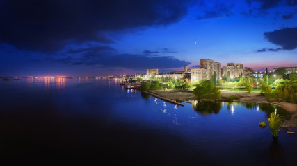 Fototapeta na wymiar Saratov city skyline at sunset, panoramic view to quay from the bridge on Volga river. Russia