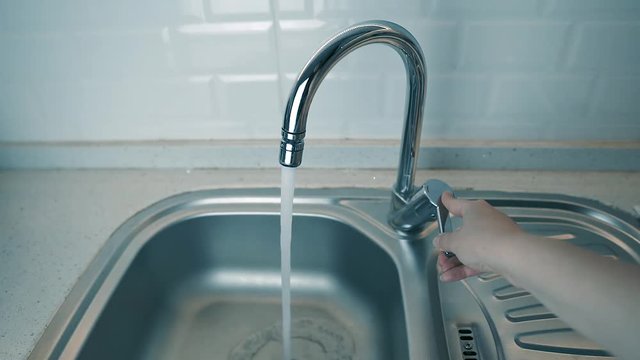 Opening Tap. Woman Hand Turn On Chrome Faucet And Water Flowing