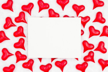 White greeting card with red hearts on white fabric background