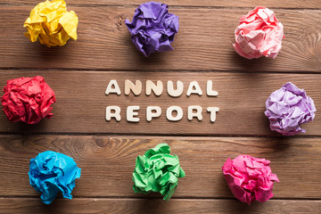 Annual report phrase on wooden table and paperballs around