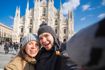 Travel, Italy and funny couple concept - Happy tourists taking a self portrait with pigeons in front of Duomo cathedral, Milan