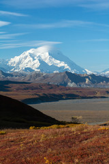 Covered in snow and clouds Mt Denali raises well above gravel foothills