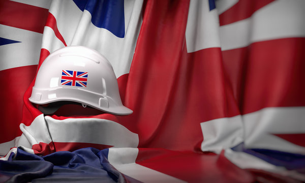 White Hard Hat Laying Over UK  Flag. Construction And Employment In United  Kingdom UK Concept, Labor Day.