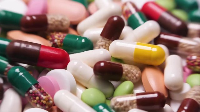 A lot of different colorful pills on rotating table. Medical backround.