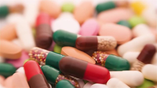 A lot of different colorful pills on rotating table. Medical backround.