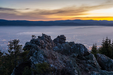 Sunrise above the town, which is covered by fog. The rock in foreground.