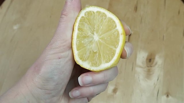 Woman hand squeeze fresh citrus lemon. Lemon juice drains from the pulp 
