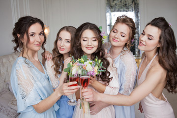 Girlfriends hug bride, bachelorette party. Beautiful young women in silk shirts having fun on the eve of the wedding of a friend.