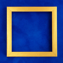 Square golden wooden frame on blue velvet background.