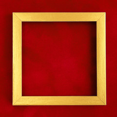 Square golden wooden frame on red velvet background.