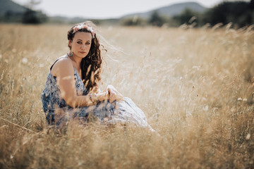 Beautiful young caucasian woman sitting on the summer grass meadow. Concept woman liberty