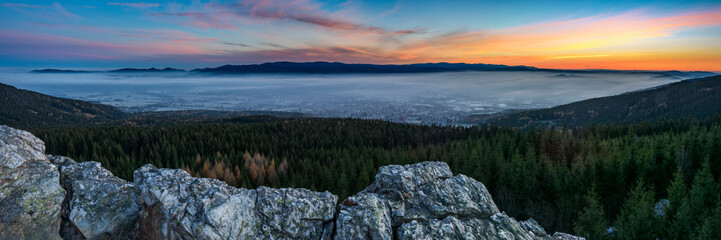 Sunrise above the town, which is covered by fog. The rock in foreground.