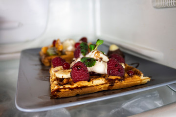 Sweet dessert in the fridge. Waffles with berries and ice cream. Summer freshness. Refreshing ice cream. Dessert with fresh berries and mint.