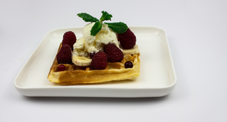 waffle with ice-cream, raspberries and bananas on a white plate. on an isolated white background. Belgian waffles. copy space