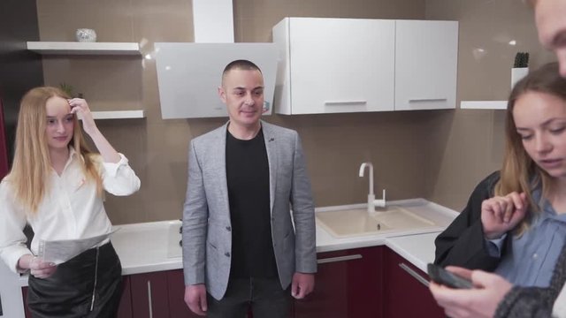 Caucasian Couple of Real Estate Brokers Staning in Kitchen With Potential Buyers. Light Camera Movement