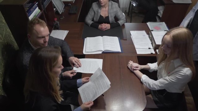 Realtor With Real Estate Brokers Gives Contract Documentation in Office To Caucasian Couple Buyers of New Property. Light Camera Movement