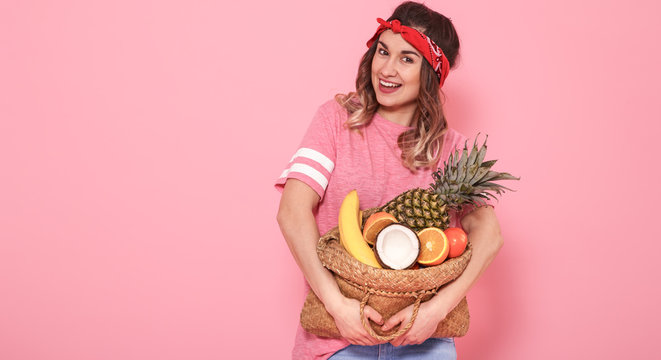 Portrait of a girl with a bag with fruit isolated on a pink background
