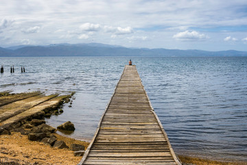 Woman resting on a old dock at the gulf of Cariaco in Venezuela