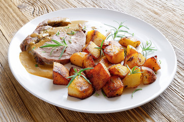 roasted lamb leg chop in gravy sauce garnished with lemon potato