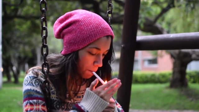 young woman smoking a cigarette in a swing
