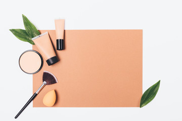 Makeup products flat lay frame on brown paper