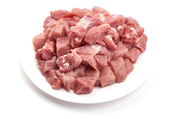 Raw pork pieces on a plate, close-up, isolated on white background