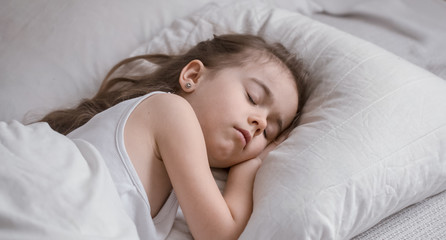 Obraz na płótnie Canvas Cute little girl sleeps sweetly in bed