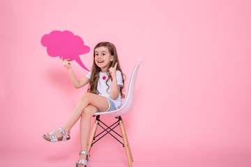 Cute little girl with an icon of a speech on a pink background