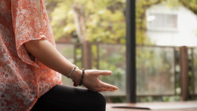Bright handheld scene: a yoga teacher during a lesson, explaining a techinque to her student. Tracking shot from the hands to the head.