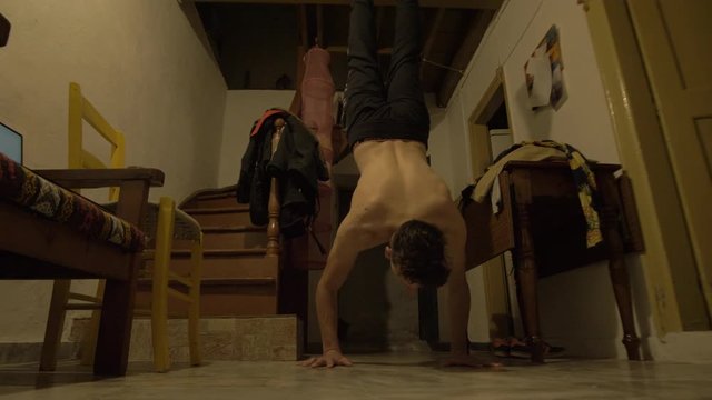 Fit young male handstand push up home workout indoors.