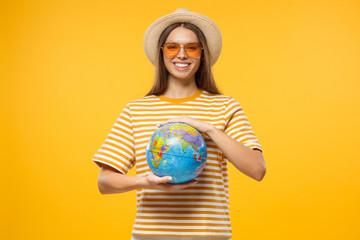 Young female in hat and sunglasses with globe in hands symbolizing freedom of travel and lifestyle, isolated