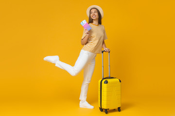 Horizontal shot of Caucasian female ready for trip with baggage and tickets, isolated