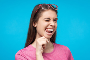 Funny female winking and pulling up her tongue feeling glad with life, isolated on background