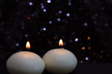 Two wax Candles Burning at Night. Yellow Candles Burning in the Dark with focus on both candles in foreground. 