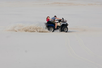 The guy and the girl ride a quad bike in the desert, having fun and enjoying, a couple of lovers