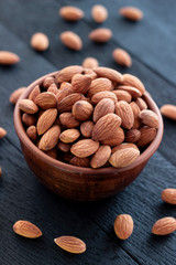 Almonds nuts in ceramic bowl on on the dark oak texture