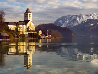 Vistas del lago Wolfgangsee con la iglesia parroquial católica a orillas del lago y las montañas nevadas al fondo, invierno de 2018