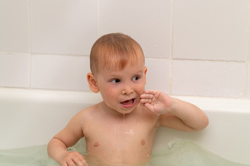 Little boy 3 years old bathes in the bath