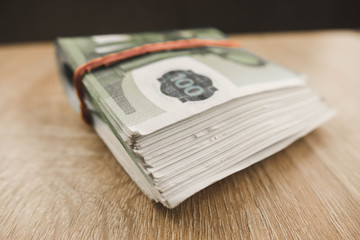 bundle of money folded in half lying on a wooden table