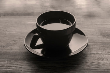 A cup of tea on a saucer on a wooden table of brown color. Hot drink in the cup. Still life.