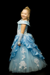 A little girl in a long, elegant dress of a princess on a black 