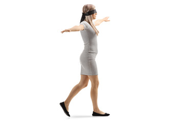 Woman wearing blindfold and walking with spread arms