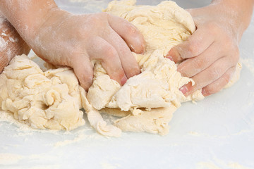 children's hands knead the dough on a light background.